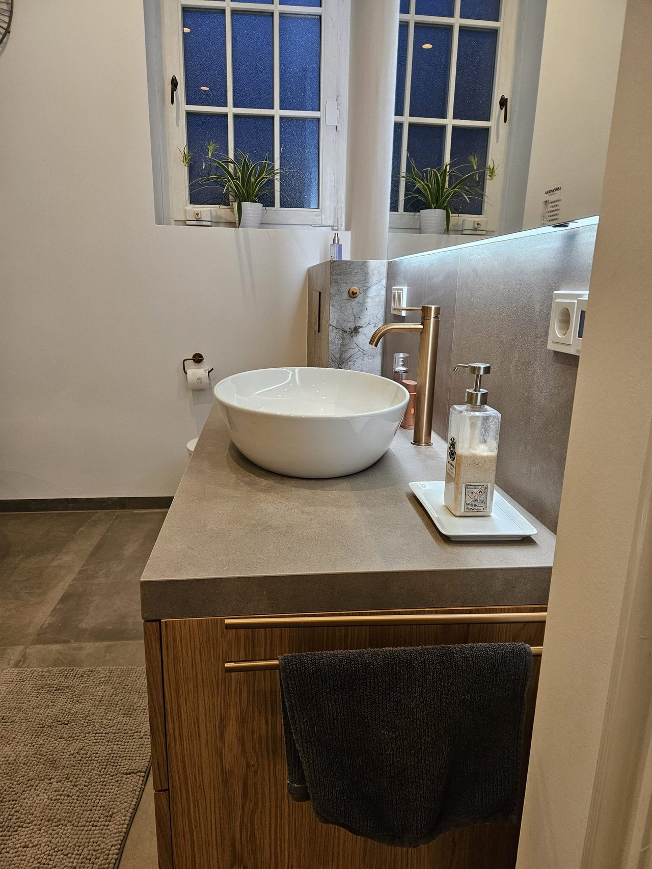 Altbau-Badsanierung mit Messingdetails – Waschtischplatte und Unterschrank in der Abendansicht