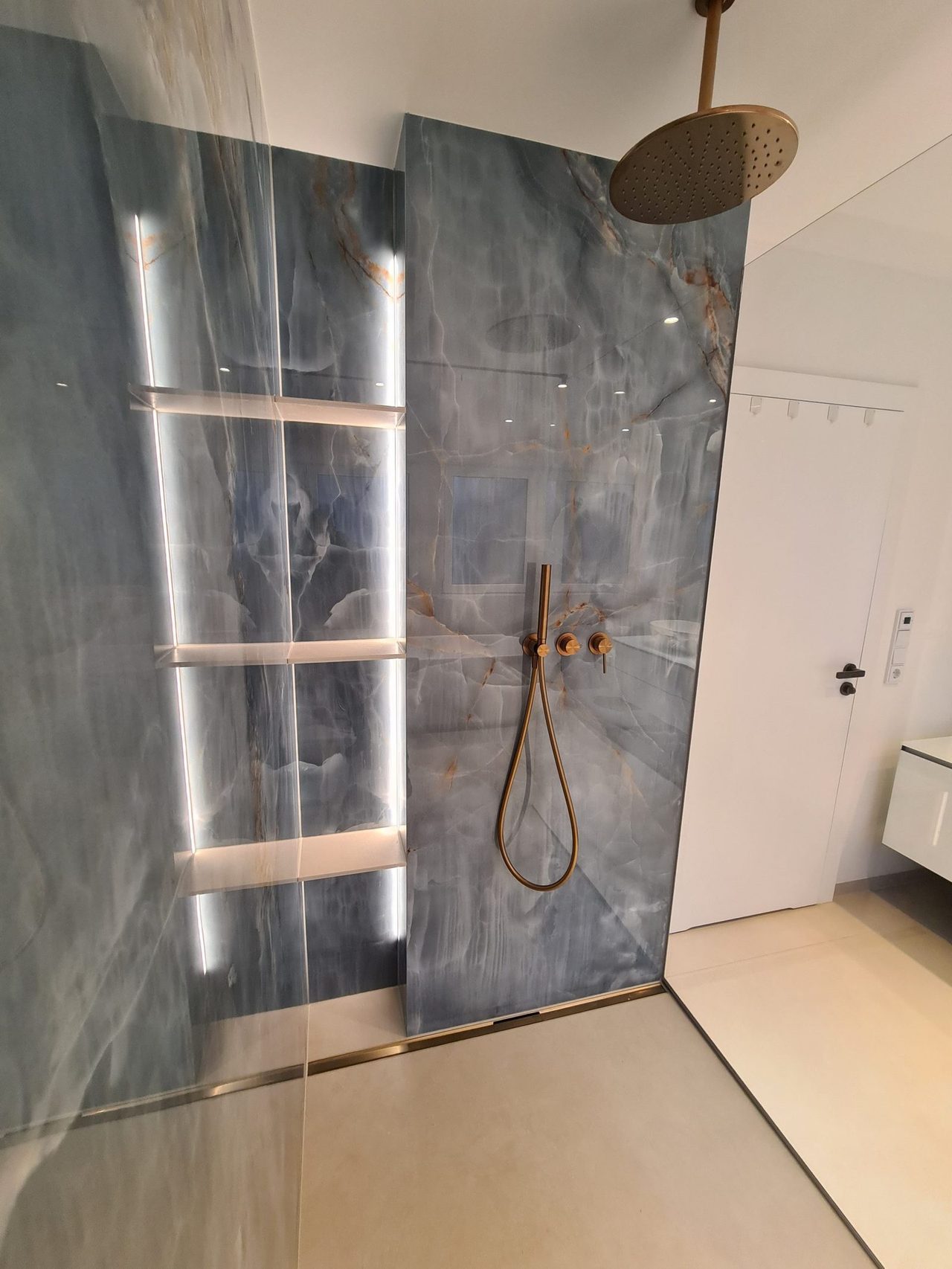 Bad in Himmelblau & Marmoroptik – Gesamtansicht der Dusche mit Lichtakzent